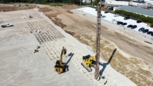 Appleton_WICK DRAIN_AGGREGATE PIER_CNC Aerial view of CNC Foundations performing aggregate pier installation at a construction site in Appleton, WI. A Komatsu excavator with a vibratory probe creates uniform pier locations for warehouse foundation stabilization.