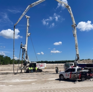 CNC Foundations crew performing rigid inclusion installation using a Soilmec SR-45 drill rig and concrete pump truck for fuel storage infrastructure. Wide site view showcasing heavy equipment setup and team coordination on compacted soil pad.