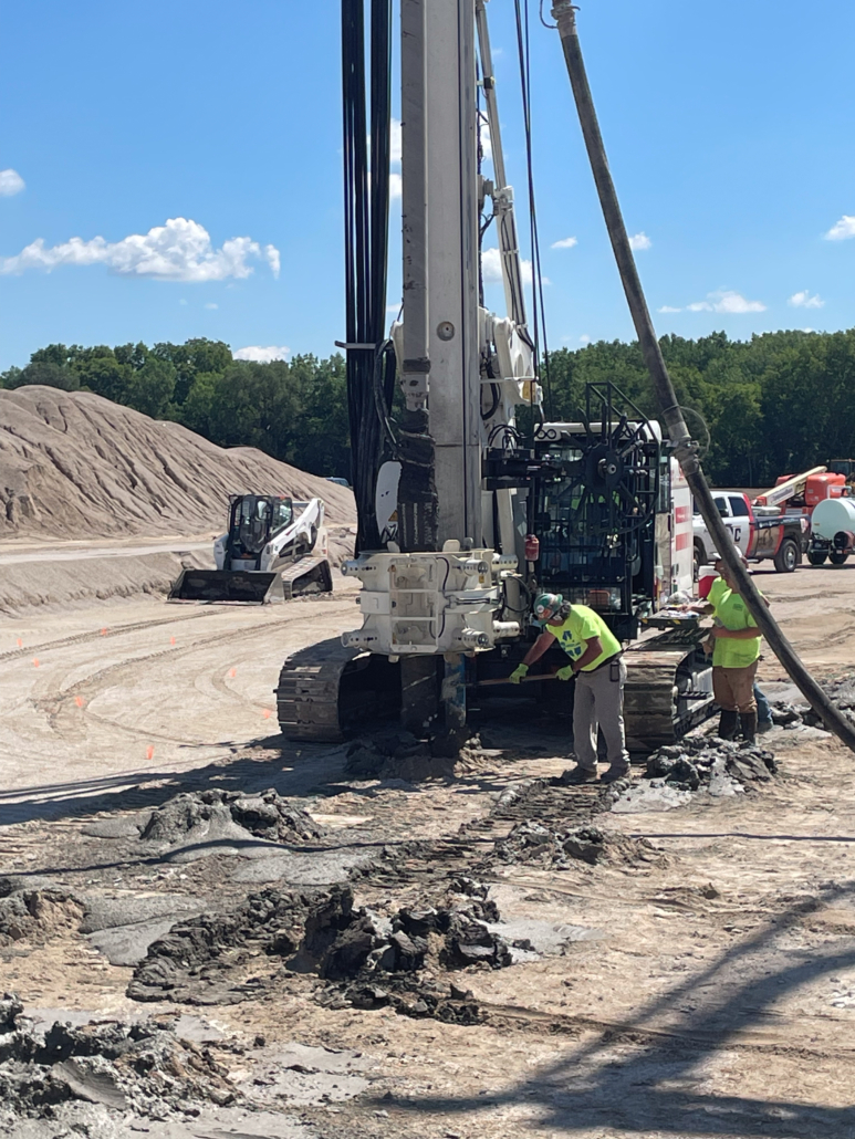 Close-up view of CNC Foundations team operating Soilmec SR-45 rig during rigid inclusion drilling. The auger tool penetrates soil as part of ground improvement for a fuel canopy foundation.