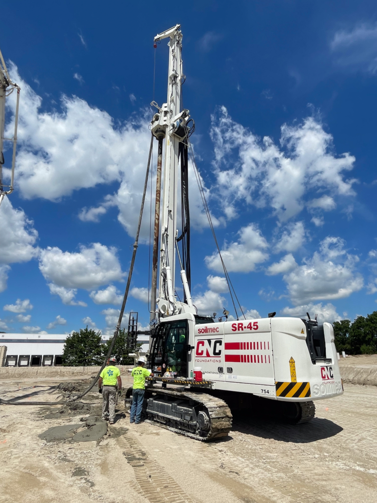 CNC Foundations operators and engineers monitor rigid inclusion installation using Soilmec SR-45 equipment. Cementitious material is placed to reinforce subgrade beneath future fuel canopy.