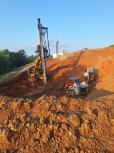 CNC Foundations crew installing aggregate piers on a steep slope using Soilmec equipment and tracked loaders in Gastonia, NC. Ground improvement methods stabilize soils for a 280,000 SF industrial logistics facility.