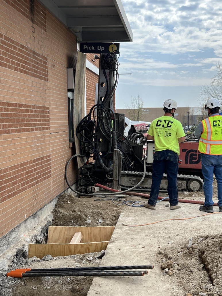 CNC Foundations crew installing a micropile foundation system outside a McDonald’s drive-thru, addressing deep fill soil conditions with specialized drilling equipment.