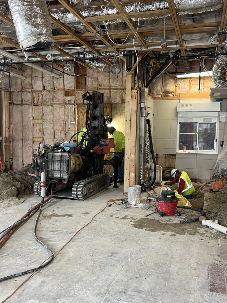 Interior view of CNC Foundations team operating micropile drilling equipment inside a McDonald’s under renovation, stabilizing the structure in deep fill conditions.