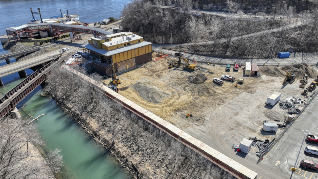 Aerial view of CNC Foundations' active job site at the Queen Marquette Casino expansion, showing full site layout, machinery in operation, and proximity to the Mississippi River and resort structure.
