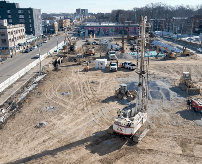 delmar loop_cnc foundations_AGGREGATE PIER INSTALLATION Aerial view of CNC Foundations' job site in the Delmar Loop, showing active aggregate pier installation across a large urban lot. The CNC drill rig, multiple pieces of construction equipment, and surrounding city buildings are visible on a clear day.